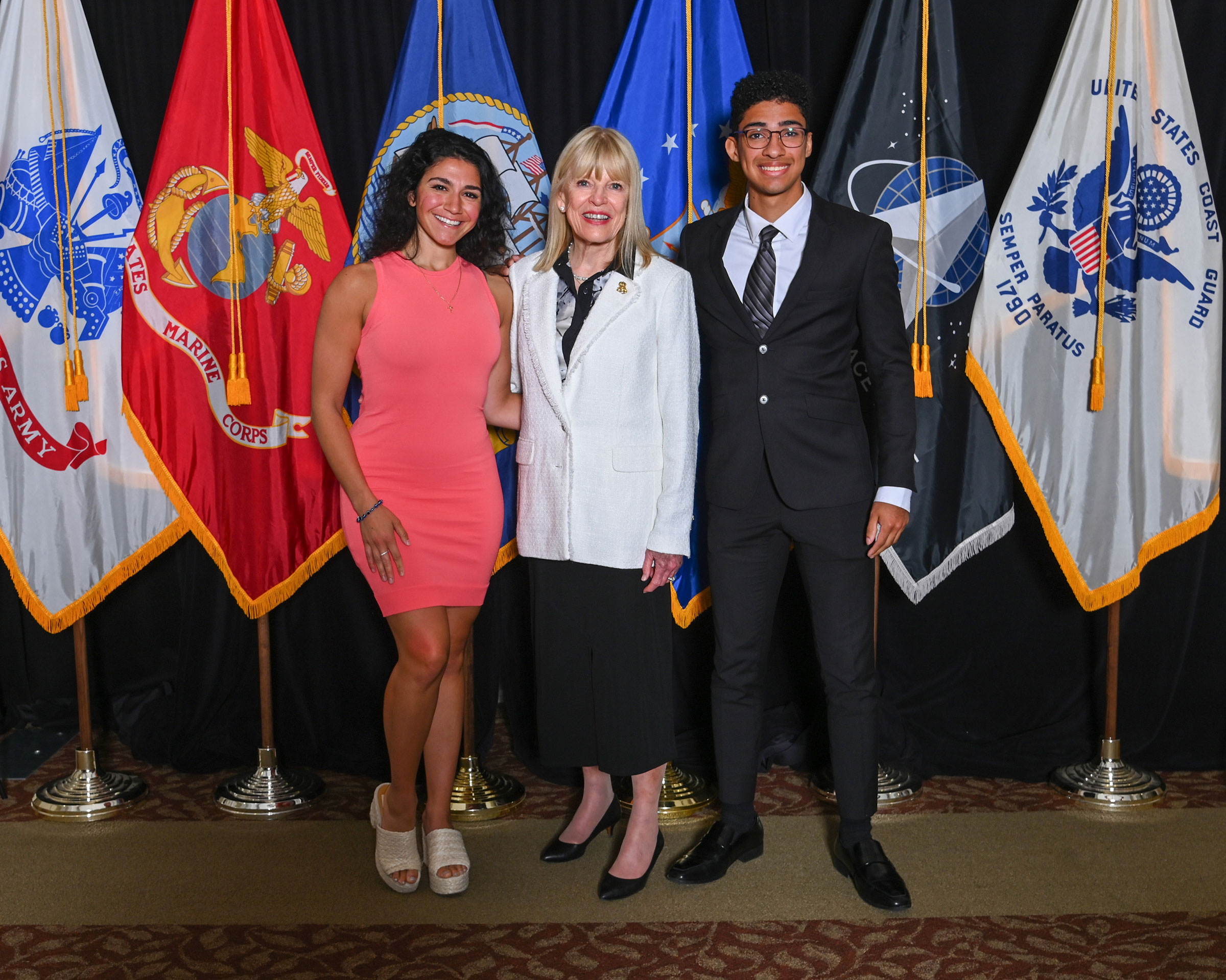 Multiple people in front of United States army flags.
