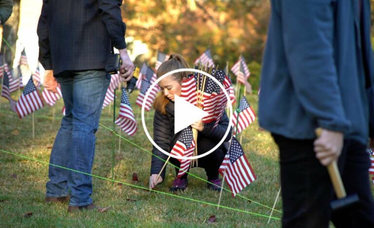 Female student veteran placing flag in the ground
